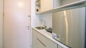 Eine kleine Küche mit einem Edelstahlkühlschrank, einer Spüle und hellen Schränken.