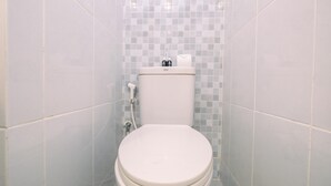 Ein Badezimmer mit einer weißen Toilette, gefliesten Wänden und einem gefliesten Boden.