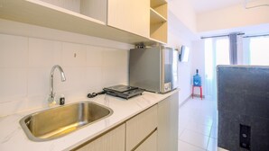 Eine moderne Küche mit Spüle aus Edelstahl, integriertem Induktionskochfeld und einem Kühlschrank.