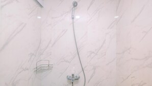 A shower with a handheld showerhead and a wall-mounted faucet, set against a marble wall. - Modern And Comfy Studio At Tokyo Riverside Pik 2 Apartment (Teluknaga)
