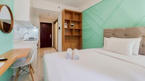 A hotel room with a bed, a desk, a chair, a wardrobe, and a mirror. - Modern Look Studio At Sky House Alam Sutera Apartment (Tangerang)