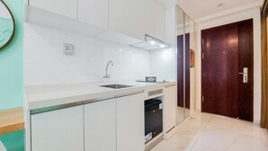 A modern kitchen with white cabinetry, a stainless steel sink, and a built-in dishwasher. - Modern Look Studio At Sky House Alam Sutera Apartment (Tangerang)