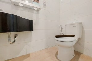 Un baño con inodoro blanco, lavamanos negro y pared de azulejos blancos.