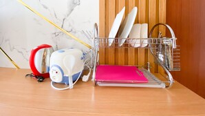 A kitchen area with a dish rack holding plates and utensils, a rice cooker, and a pink tray. - Cozy Living Studio (No Kitchen) At Sentraland Semarang Apartment (Semarang)