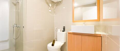 A modern bathroom with a glass-enclosed shower, a toilet, and a wooden vanity with a mirror.