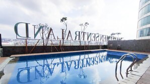 A rooftop swimming pool with clear reflections, surrounded by a stone deck and a view of the cityscape. - Cozy Living Studio (No Kitchen) At Sentraland Semarang Apartment (Semarang)
