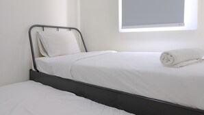 A single bed with white bedding and a rolled towel, a window with blinds, and a plain wall. - Modern Look 2Br At Apartment Parahyangan Residence (Bandung)