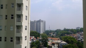 A high-rise building with multiple balconies, surrounded by a densely packed urban area with various buildings and greenery.