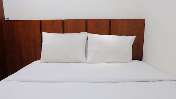 A bed with a wooden headboard and white bedding.
