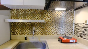 A kitchen with a tiled backsplash, a stainless steel sink, and a red electric stove.