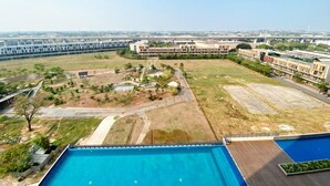 A large swimming pool with a surrounding deck, a parking area, and a landscaped garden with pathways.