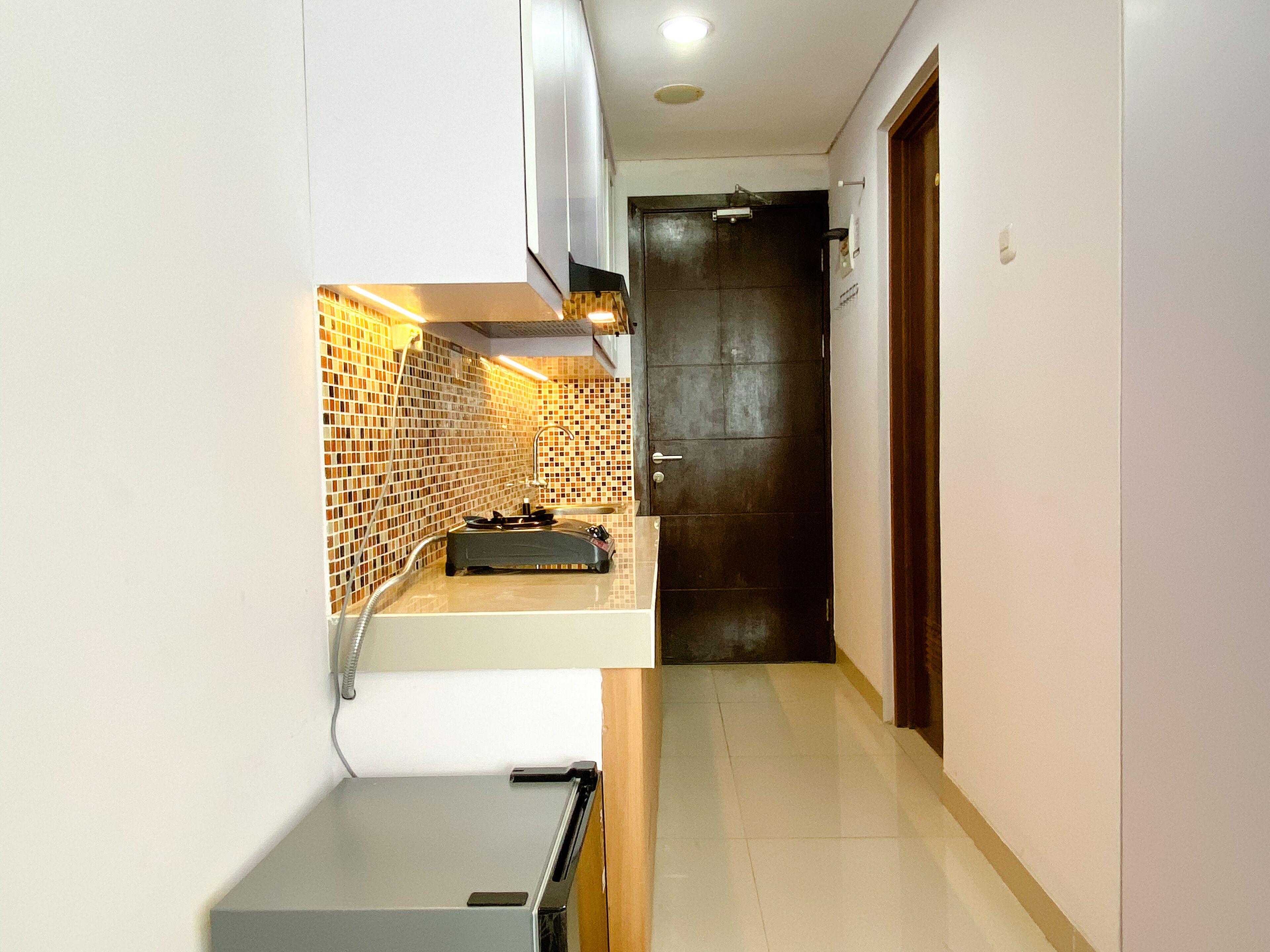 A narrow hallway with a kitchen area featuring a tiled backsplash and a sink.
