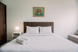 Restful retreat with a neatly made bed, bedside table, and elegant artwork.