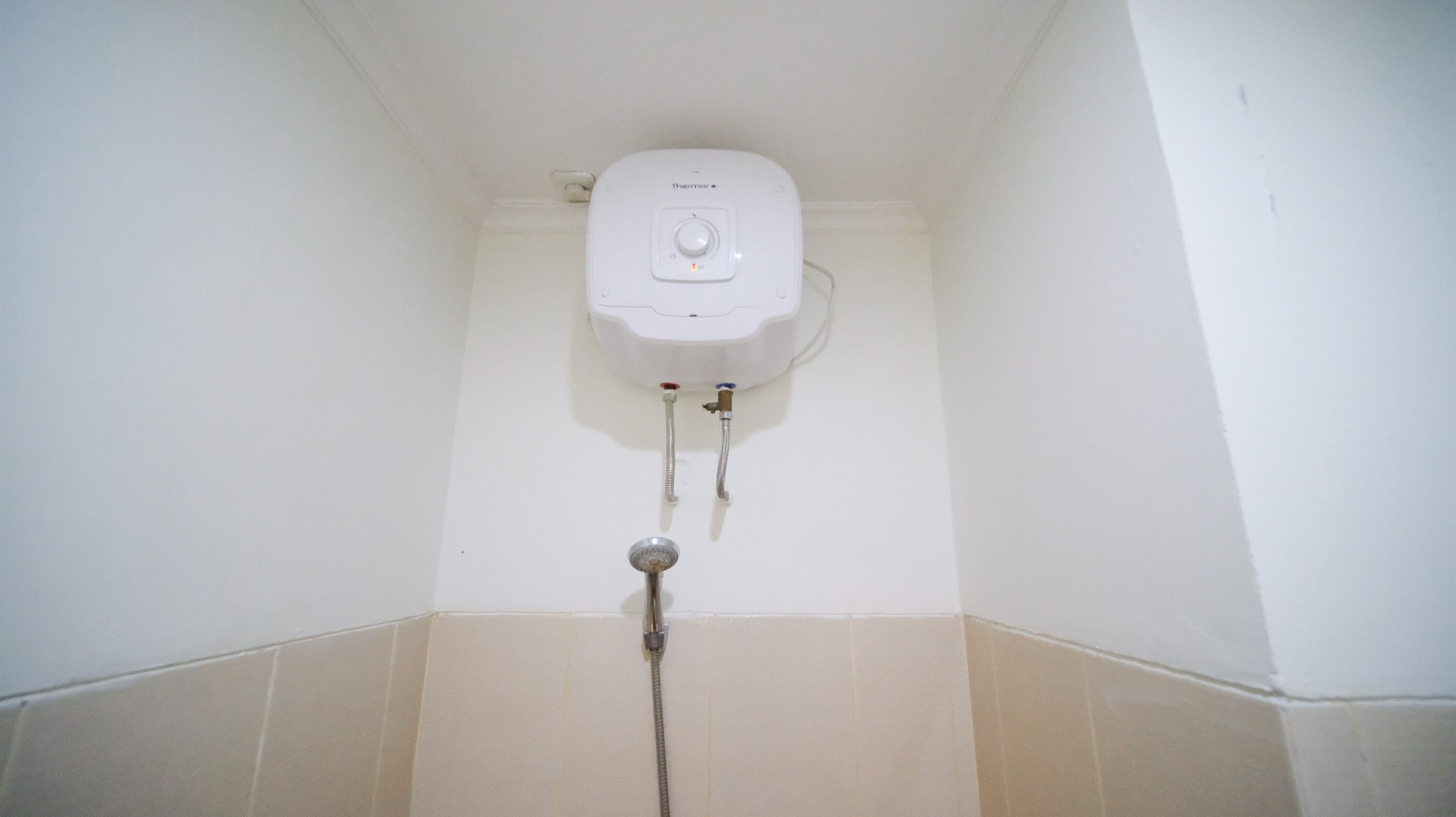 Une cabine de douche blanche dotée d’un panneau de commande et de deux tuyaux.