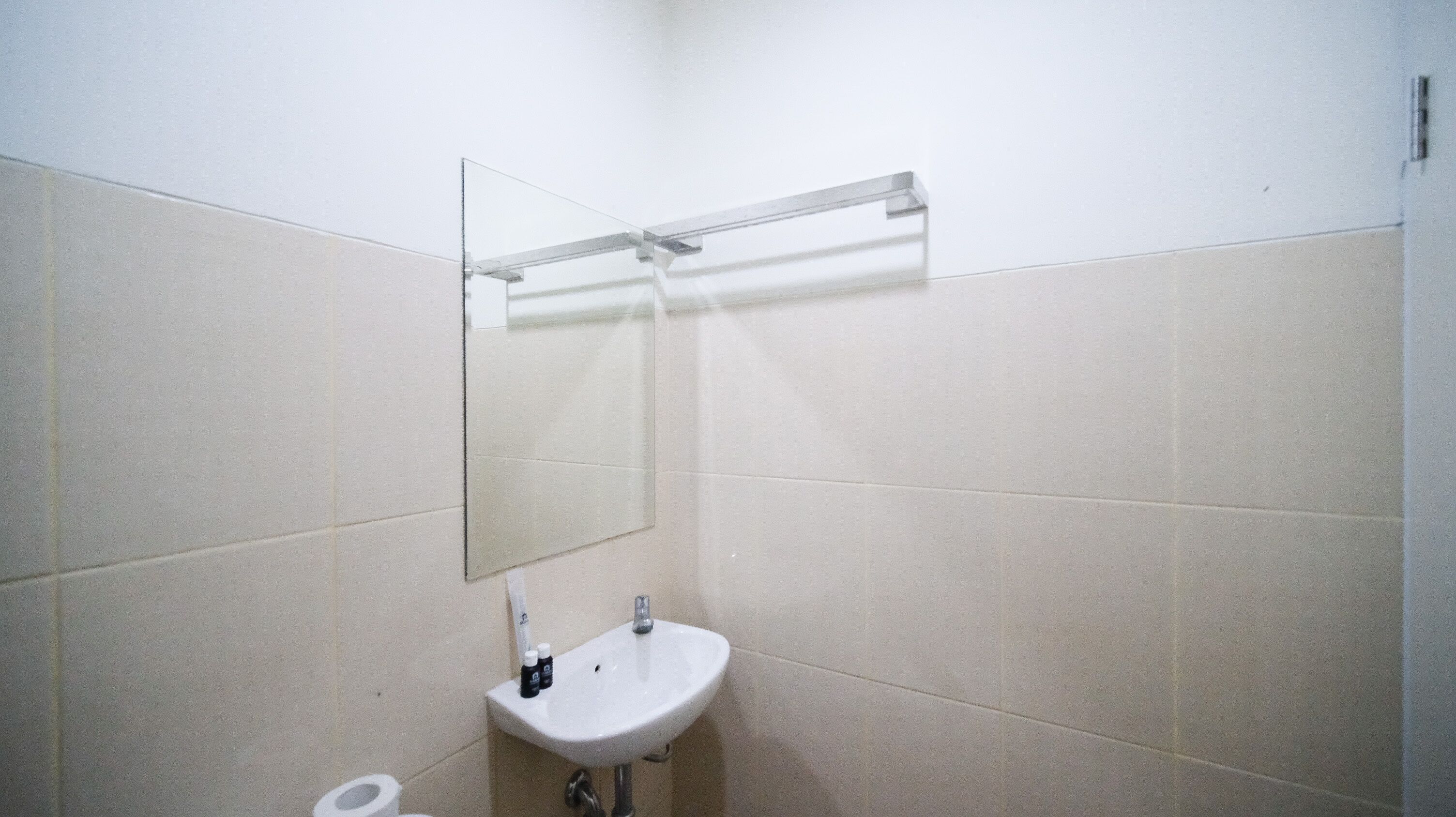 A bathroom with a white sink, a mirror, and a towel rack.
