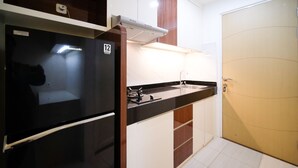 A compact kitchen with a refrigerator, stove, sink, and cabinets. - Compact And Cozy Stay Studio At Bale Hinggil Apartment (Surabaya)