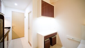 A hallway with a white door, a wooden cabinet, and a white countertop. - Compact And Cozy Stay Studio At Bale Hinggil Apartment (Surabaya)