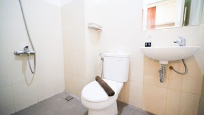 A small bathroom with a toilet, a shower, and a sink. - Compact And Cozy Stay Studio At Bale Hinggil Apartment (Surabaya)
