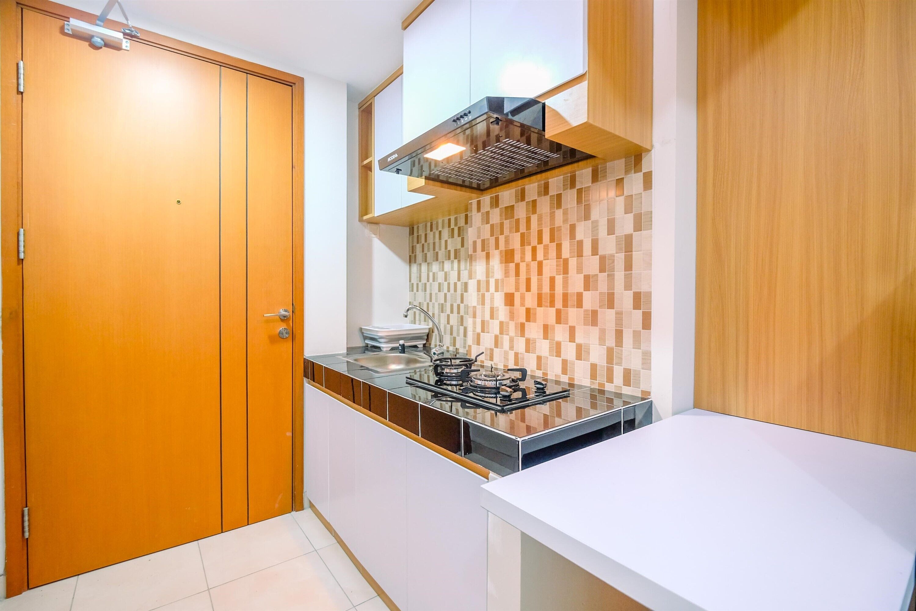 A compact kitchen with a stove, sink, and wooden cabinets.
