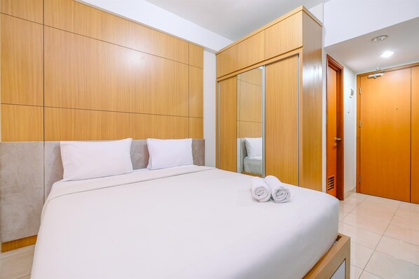 A hotel room with a bed, wooden wardrobe, and a mirror. - Simply Look Studio At Margonda Residence 5 Apartment (Depok)