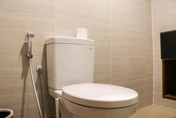 A modern bathroom with a toilet, a shower hose, and a toilet paper holder.