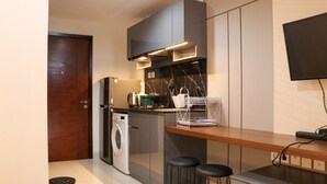 A compact kitchen with a washing machine, a wooden countertop, and a TV mounted on the wall. - Nice And Homey Studio At West Vista Apartment (Jakarta)