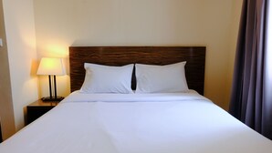 A neatly made bed with white linens and a wooden headboard. - Modern Look 3Br At Apartment Braga City Walk (Bandung)