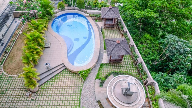 Ein Luftbild eines Resorts mit Swimmingpool, Liegebereichen und einem kreisförmigen Wasserspiel.