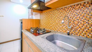 Eine Küche mit Gasherd, Edelstahlspüle, Holzschränken und einer gefliesten Spritzschutzwand.