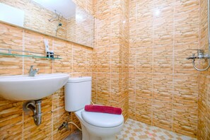 Bathroom features a stone-patterned wall, a white sink with a chrome faucet, a toilet, and a glass shelf above the sink.