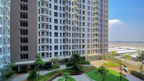 A high-rise residential building with multiple balconies and a landscaped courtyard. - Simply And Homey Studio Tokyo Riverside Pik 2 Apartment (Teluknaga)