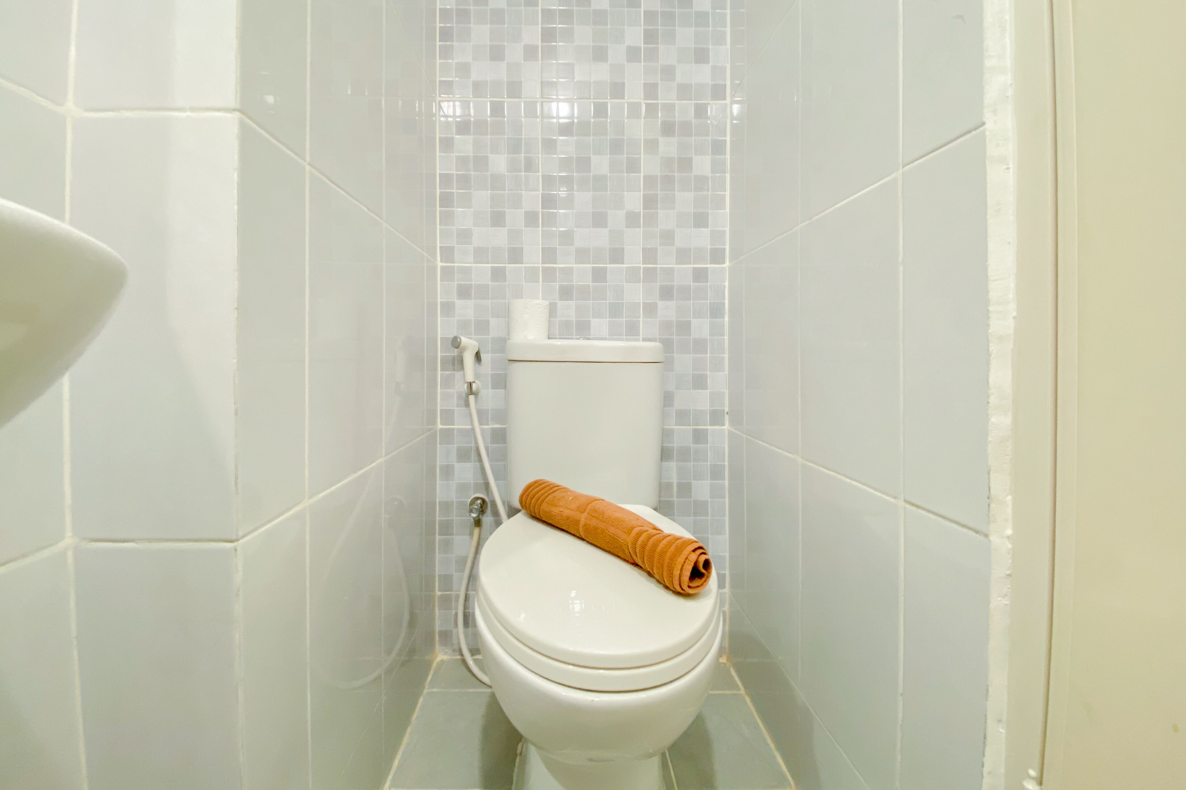 A bathroom with a white toilet, a shower, and a tiled wall.