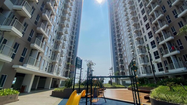 A residential building with multiple balconies and a playground area with slides and swings. - Simply And Homey Studio Tokyo Riverside Pik 2 Apartment (Teluknaga)