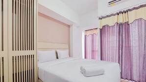 Una habitación de hotel con cama, armario de madera y ventana con cortinas.