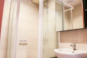 A bathroom with a glass shower enclosure, a sink with a faucet, and a mirror above the sink.