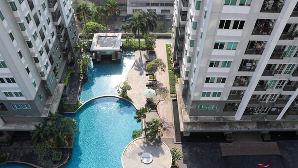 A high-rise hotel with a central swimming pool, surrounded by balconies and greenery. - Full Furnished With Comfort Design 2Br Apartment At Thamrin Residence (Jakarta)