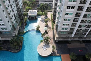 Un hotel de gran altura con una piscina central, rodeado de balcones y vegetación.
