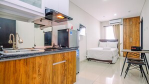 Een moderne hotelkamer met kitchenette, een bed, een eethoek en een ruime inloopkast.