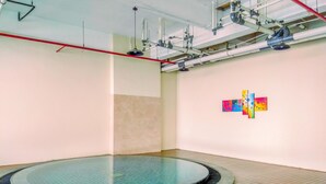 Een modern binnenzwembad met betegelde vloer en een plafond met zichtbare leidingen.