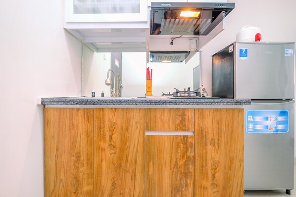 A kitchen with wooden cabinets, a stainless steel refrigerator, and a built-in oven.