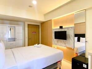 Comfortable room with a neatly made bed, wardrobe, and TV.