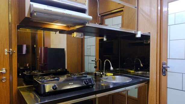 A kitchen with a stove, sink, and overhead ventilation. - Strategic 2Br At Tamansari Panoramic Apartment (Bandung)