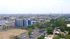 A cityscape with modern buildings, a wide road, and surrounding greenery. - Strategic 2Br At Tamansari Panoramic Apartment (Bandung)