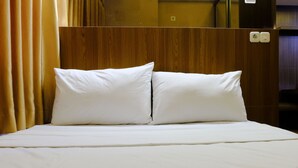 A hotel room with a wooden headboard, two white pillows, and a bed with a white bedspread. - Strategic 2Br At Tamansari Panoramic Apartment (Bandung)