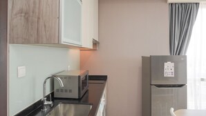 A modern kitchen with a stainless steel sink, a microwave, and a refrigerator. - Modern Look And Comfy 2Br Menteng Park Apartment (Jakarta)