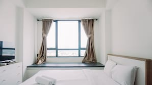Ein Hotelzimmer mit Bett, einem Vorhangfenster, einem Fernseher auf einem Schrank und Blick auf den Strand.