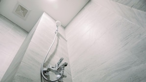 Eine Dusche mit Handbrause und Wandarmatur in einem gefliesten Raum.