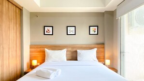 A hotel room with a large bed, two bedside lamps, and three framed pictures on the wall.