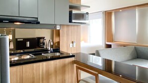 A modern kitchen with grey cabinets, a black countertop, a stainless steel sink, a microwave, and a built-in oven.