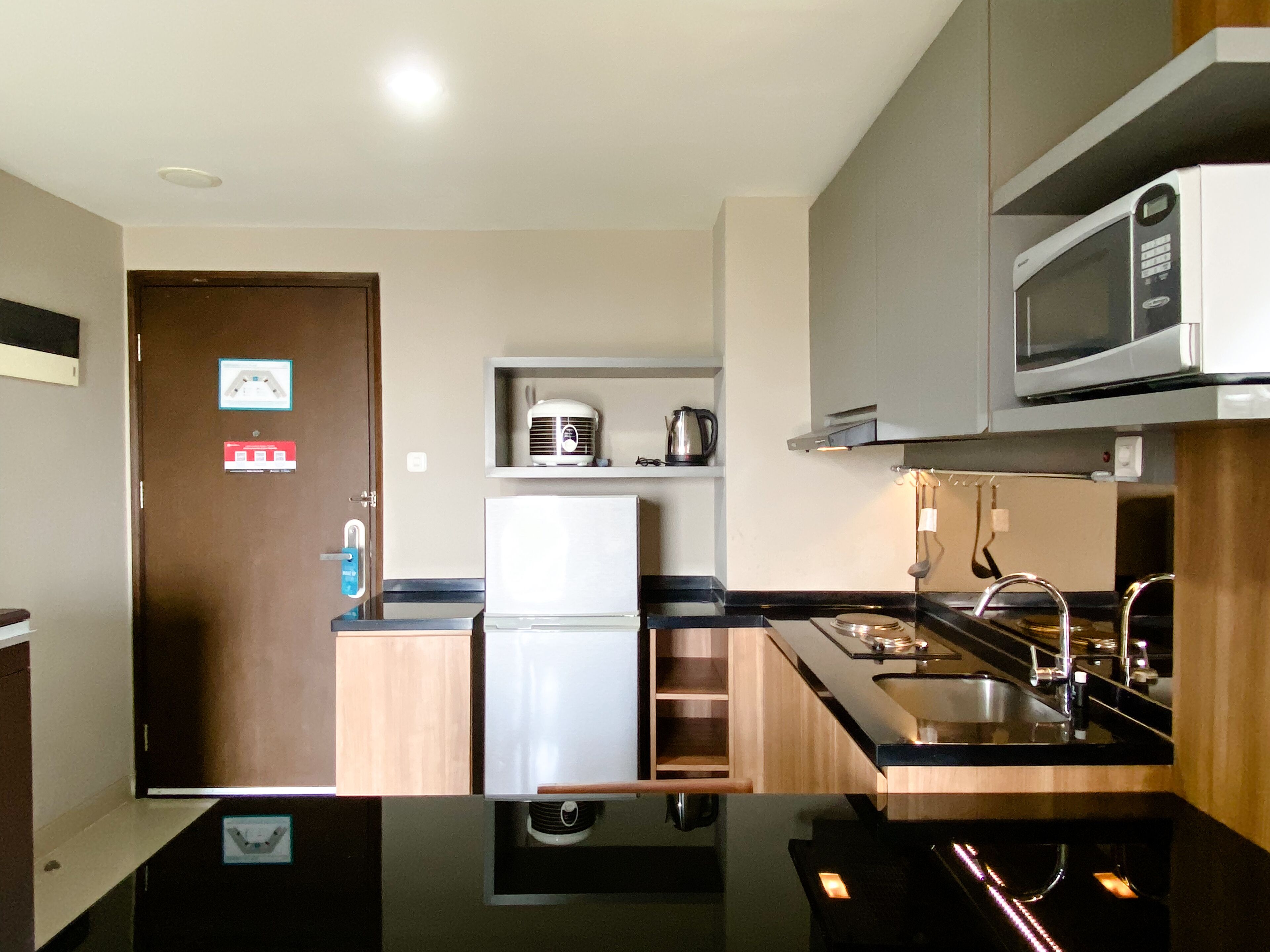 Una cocina moderna con refrigerador, microondas, pileta y armarios de madera.